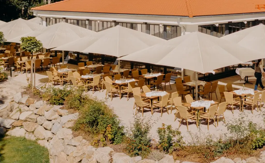 Sonnige Terrasse mit eingedeckten Tischen und weißen Sonnenschirmen zum Verweilen.