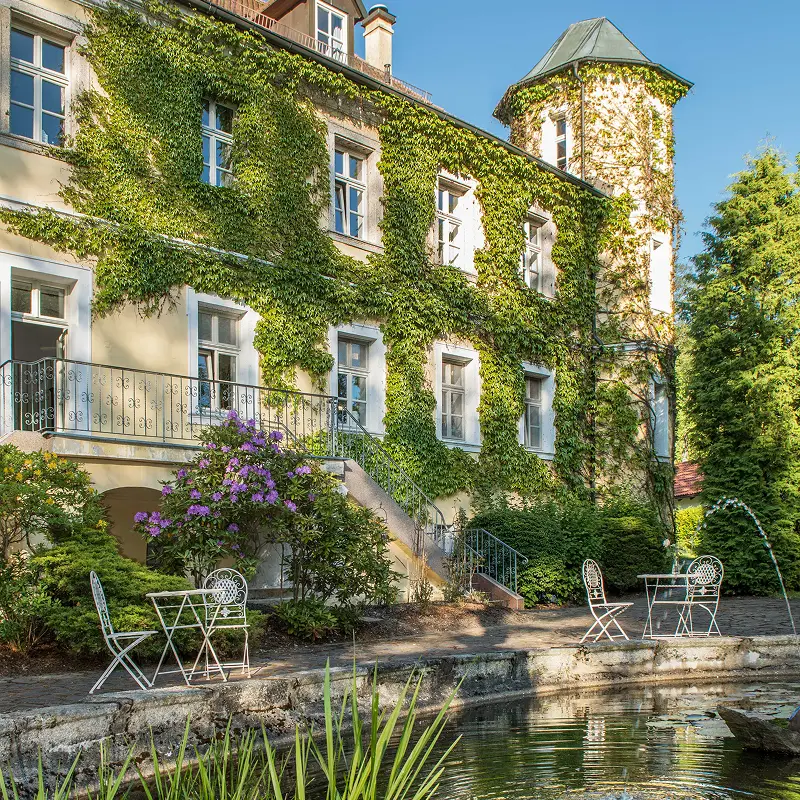 Historisches Landschloss Albenhof mit efeubewachsener Fassade im Sonnenschein.